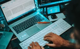 Tech-savvy workspace showing coding activity across a laptop, keyboard, and monitors.