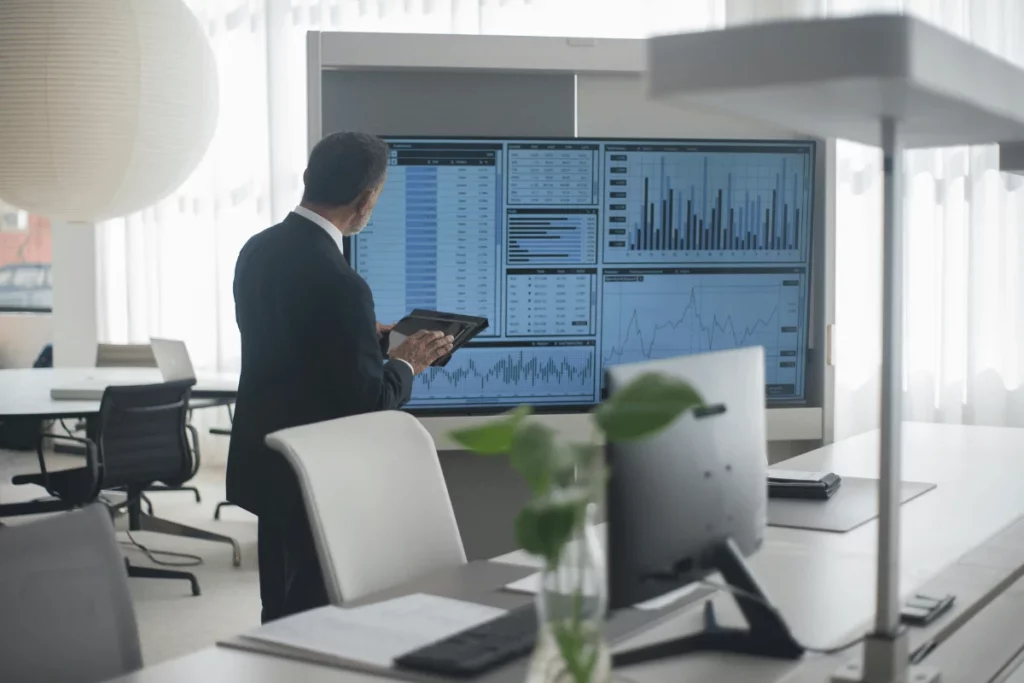 Businessman analyzing financial charts on large screen.