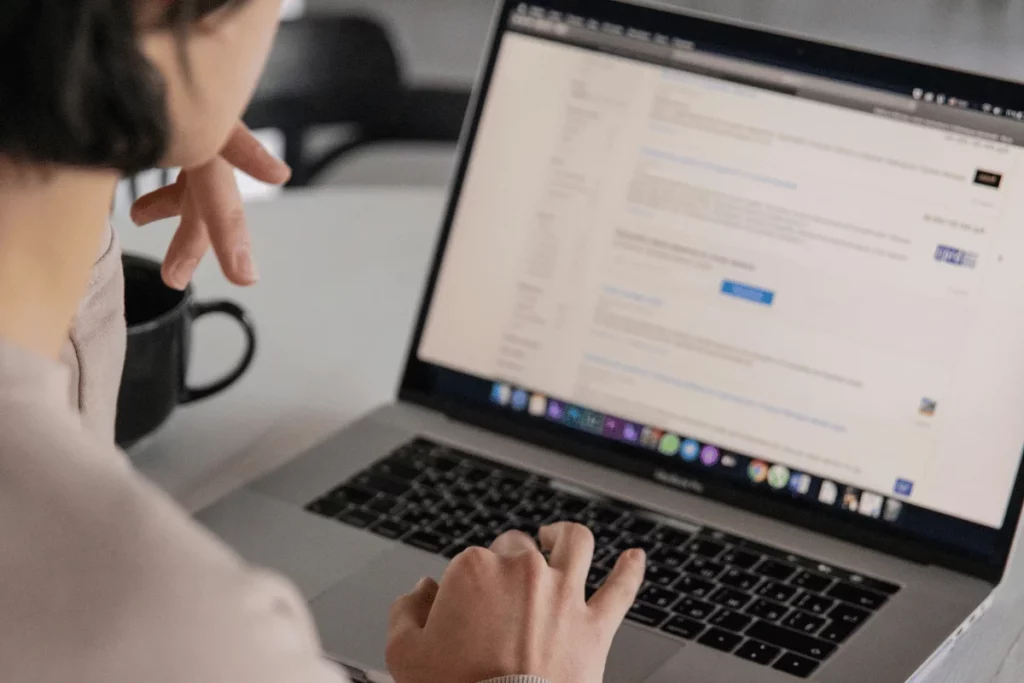 Freelancer typing on a laptop while analyzing information on screen in a minimal home office.