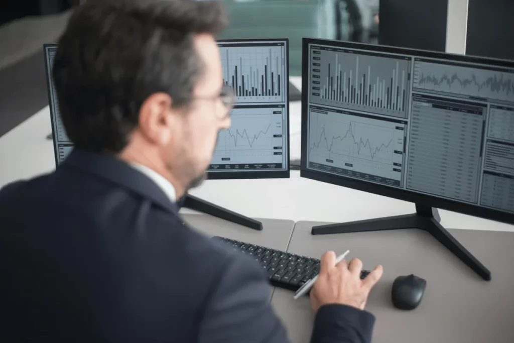 Businessman analyzing financial charts on multiple monitors.